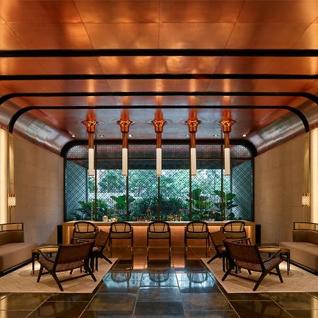 The Ruma Hotel And Residences Куала Лумпур Екстериор снимка The image shows a stylish interior space with a modern and elegant design. The walls have a sleek, warm-toned finish, and there are large windows that provide natural light. The ceiling features striking architectural lines, likely in a metallic mate
