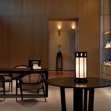 The Ruma Hotel And Residences Куала Лумпур Екстериор снимка The photo shows a modern, minimalist interior space. It features a wooden wall with soft lighting, enhancing a calm atmosphere. In the foreground, there is a round table with a uniquely designed lamp on it. Surrounding the table, there are stylish wo