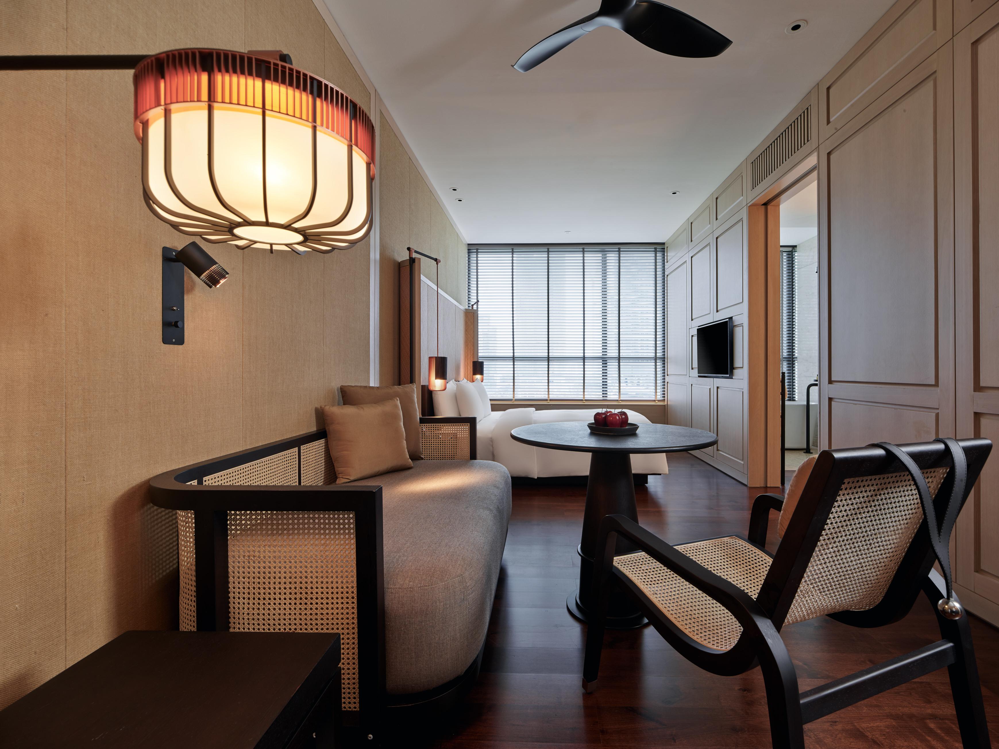 The Ruma Hotel And Residences Куала Лумпур Екстериор снимка The photo shows a stylish and modern interior of a hotel room or a living space. The decor features warm tones and natural materials, with a wall finished in light wood or beige. 

In the foreground, there is a round table with a small decorative ite